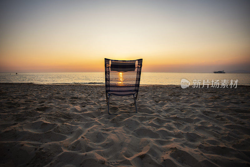 日落时坐在海滩上的椅子上