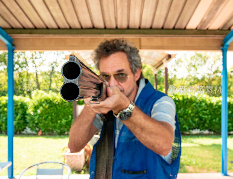 一个成年人在户外射击场用双管猎枪瞄准的肖像