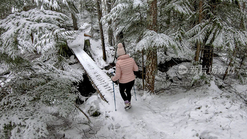 女性徒步旅行者接近积雪覆盖的木板路