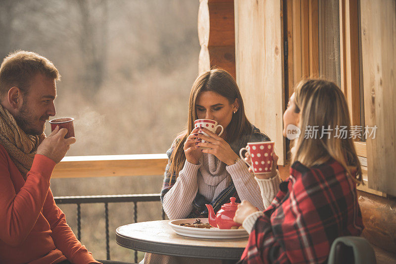 三个年轻人一起在户外的院子里喝茶