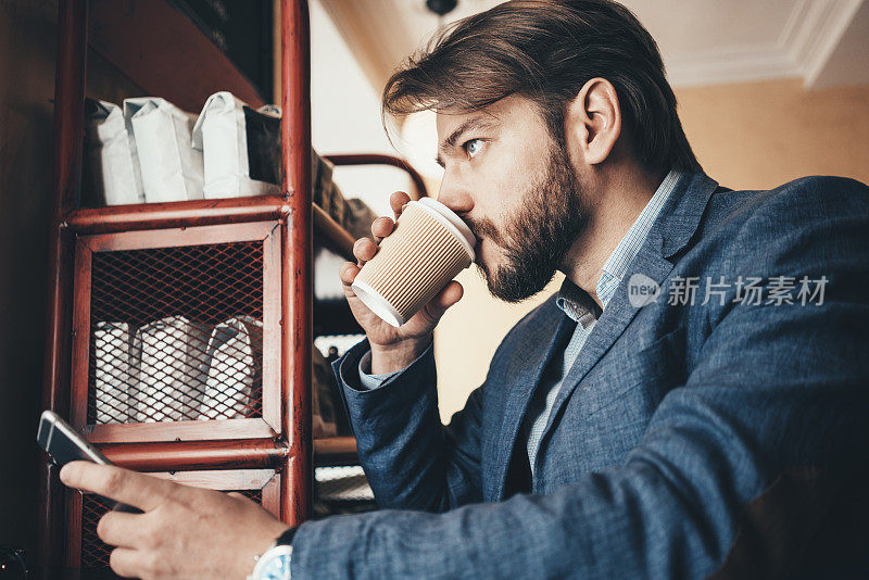 年轻人穿着休闲装坐在咖啡馆里用手机，喝着咖啡
