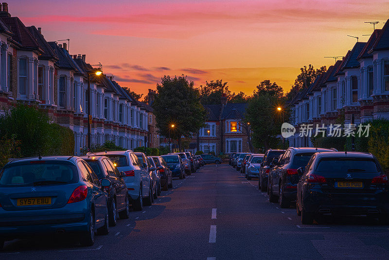 在伦敦西汉普斯特德附近的居民湾，一排房子和汽车停放在街道上的日落