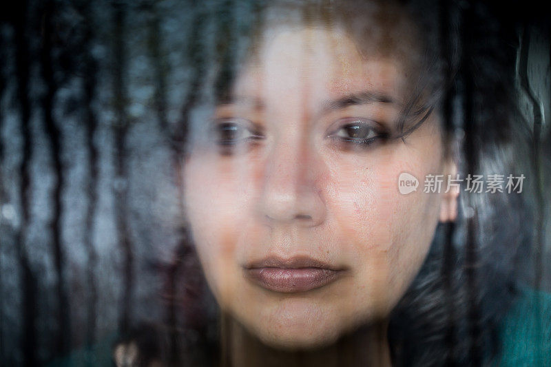 沮丧的女人望着下雨的窗外