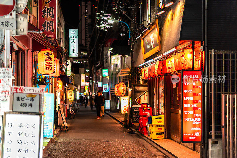 新宿区市中心的街道上有居酒屋的夜间餐馆和大久保车站附近的标志