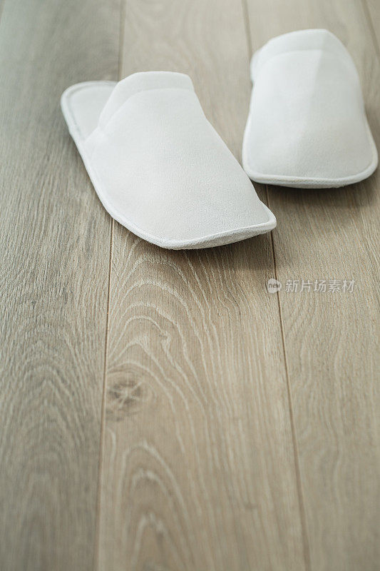 木地板上放着一双舒适的白色拖鞋