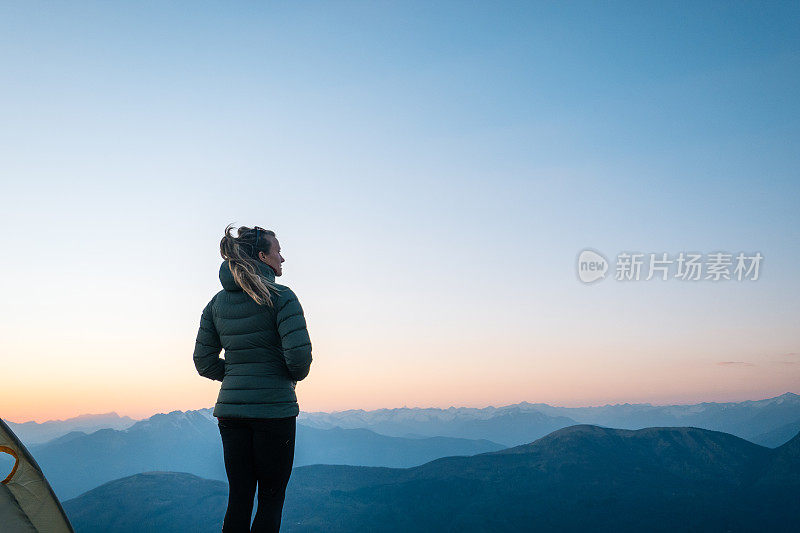 年轻女子在露营帐篷外看日出