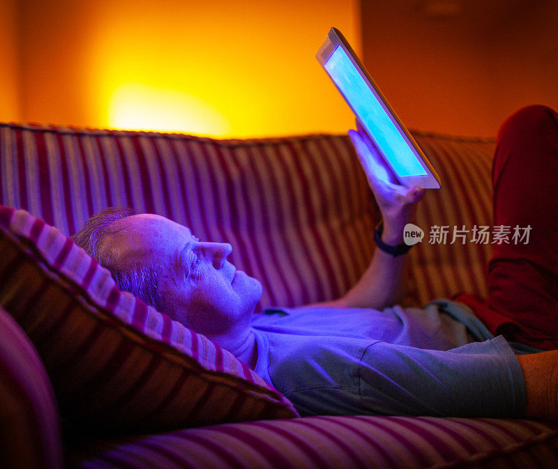 手机发出的蓝光照射在夜间阅读的人的脸上