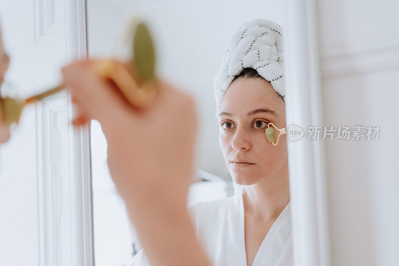 在家里用玉滚筒擦脸的女人