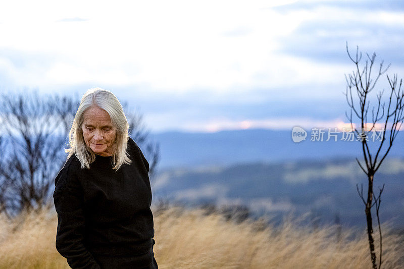 现代，迷人的成熟女人的肖像俯视和站在傍晚的风景，背景与复制空间