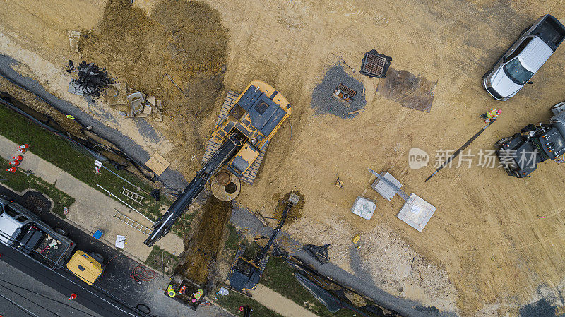 挖掘机在施工现场进行第一阶段土方工程，附近有一条道路。