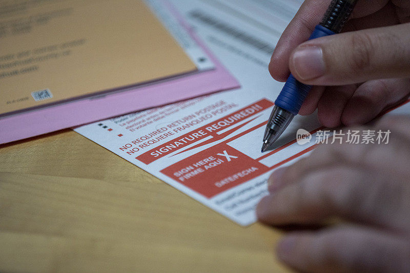 缺席选票表格用男子的手用钢笔签名，手指握着表格，左侧空白