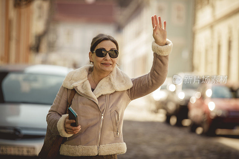 一个成熟的女人在城市的街道上叫出租车