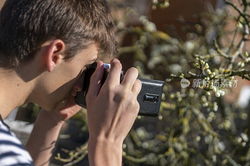 一个年轻人在花园里拿着一台老式的中画幅摄影机