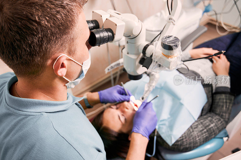 牙医用诊断显微镜检查妇女的牙齿。
