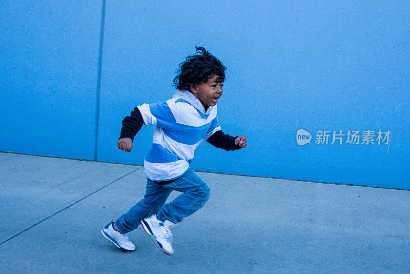 小混血男孩在蓝色的墙上跑