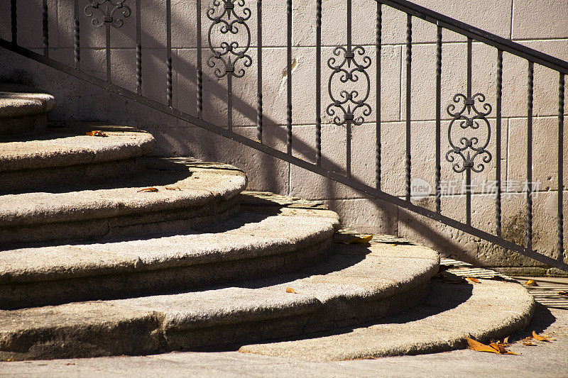 阳光下的古石楼梯和铸铁栏杆。