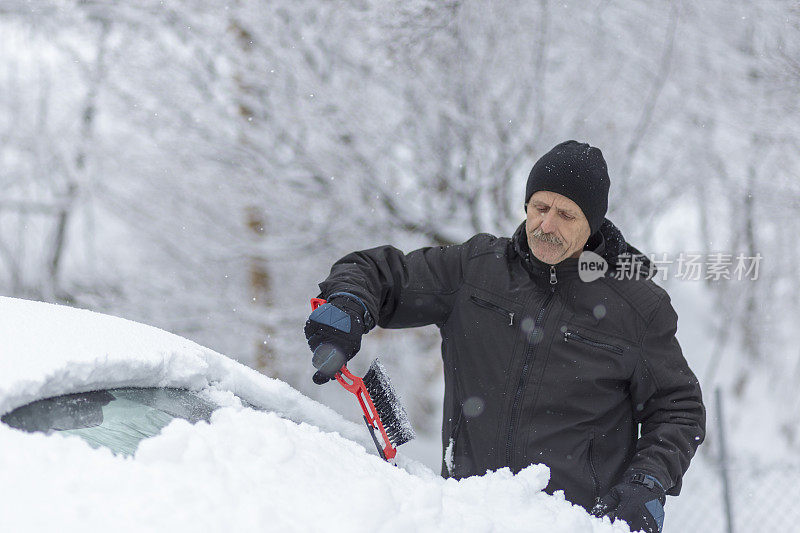 一名男子正在竭尽全力清除车上的冰雪