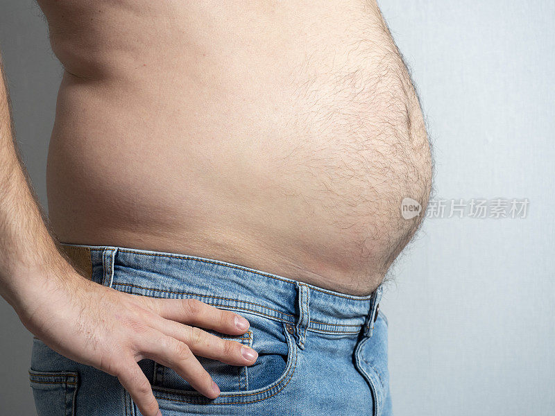 一个穿着牛仔裤的胖男人的侧面。男性肥胖的问题。