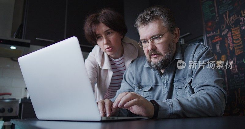 一对成熟的夫妇正在讨论他们看笔记本电脑屏幕的计划