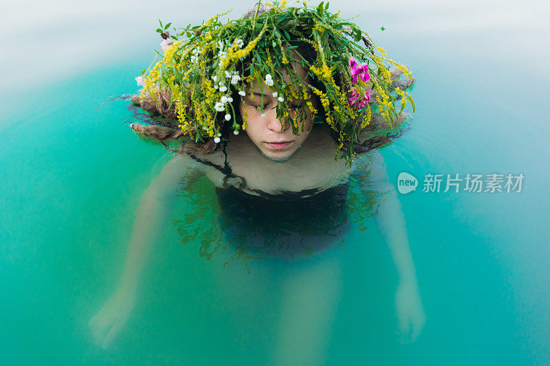 在夏季库帕拉夜，年轻女子戴着花环在湖中游泳
