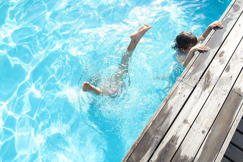 女孩，白种人的孩子，在室外游泳池游泳。两个朋友潜入水中。