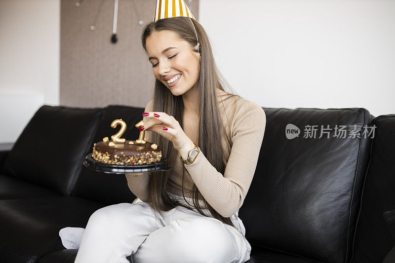 年轻漂亮的女人在家里用巧克力蛋糕庆祝她21岁的生日