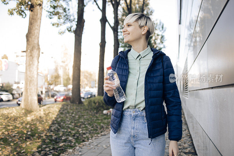 一个快乐的女孩散步的肖像，并带来一个可重复使用的水瓶