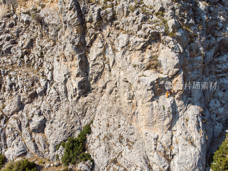鸟瞰图的女性高山攀岩者正在攀登一座小山的顶峰