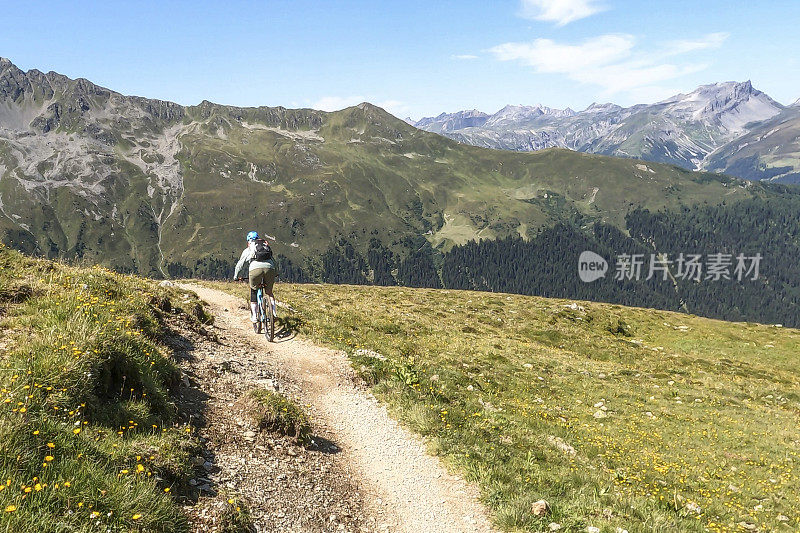 女人沿着阳光明媚的自行车道骑山地车