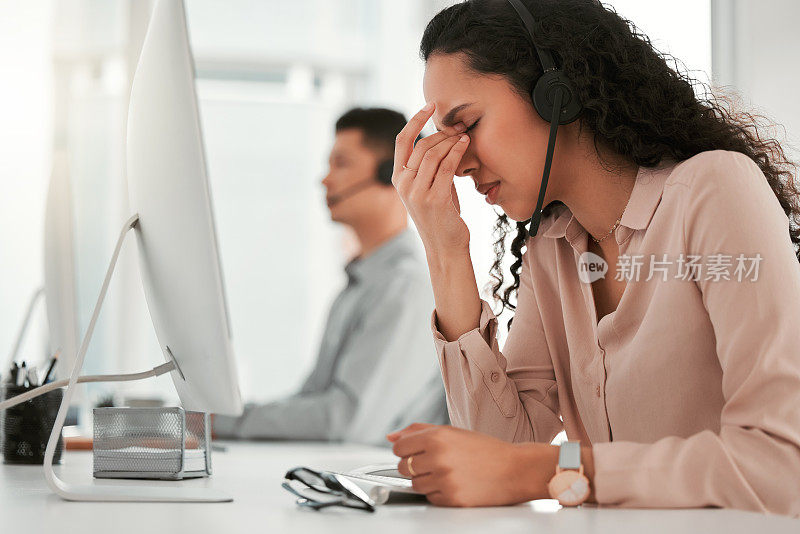 一名年轻的女性呼叫中心工作人员在办公室里头痛