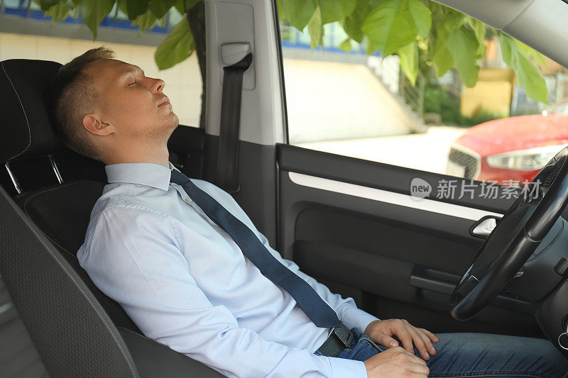 一个疲惫的年轻人睡在他的现代车里