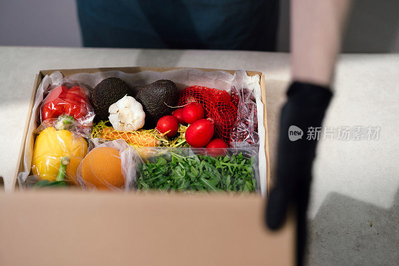 近距离的女性手打开包装盒与新鲜的蔬菜和水果