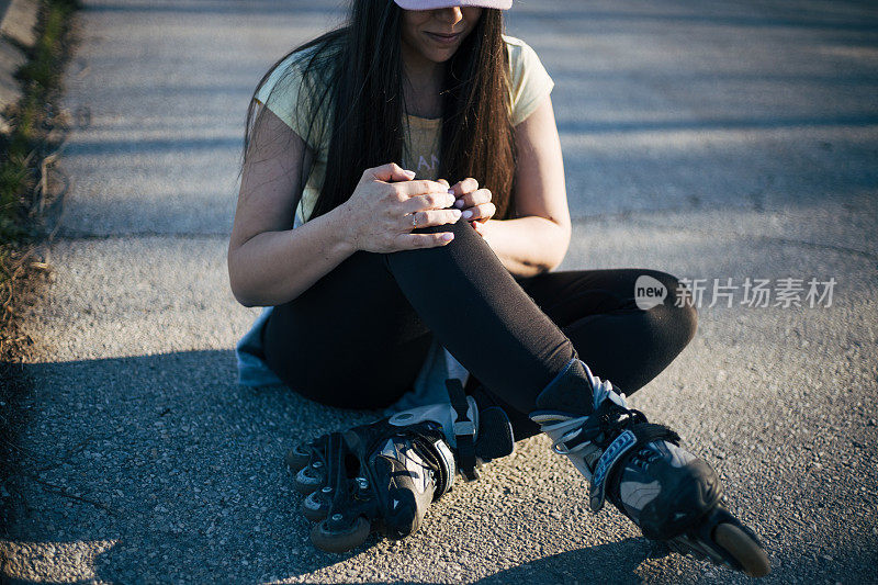 女孩戴着帽子骑旱冰鞋摔倒了