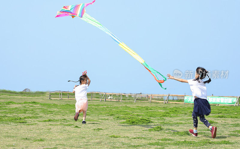 亚洲女孩在草地上玩和放风筝。