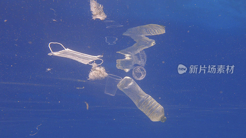 塑料瓶、杯子和医用口罩在蓝色的水中畅游。废弃的塑料和其他碎片在阳光下缓慢地漂浮在蓝色的水面下。海洋塑料污染。埃及红海