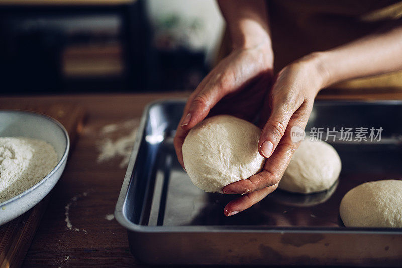 将面团放入金属托盘准备烘焙的手的特写