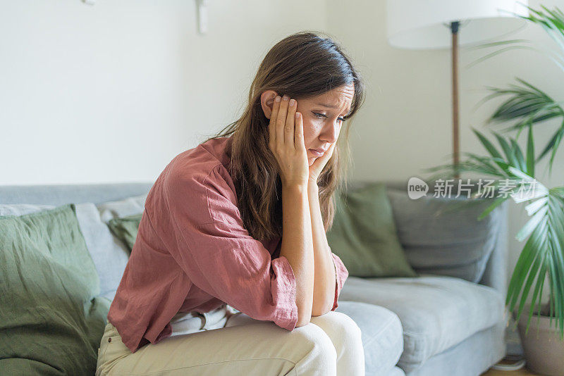 悲伤的年轻女子坐在客厅的沙发上