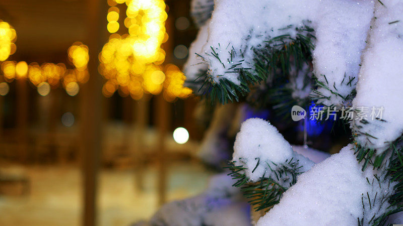 圣诞树上的雪花特写，装饰好的圣诞树和装饰城市房屋的彩灯创造了神奇的新年气氛。圣诞节的准备。