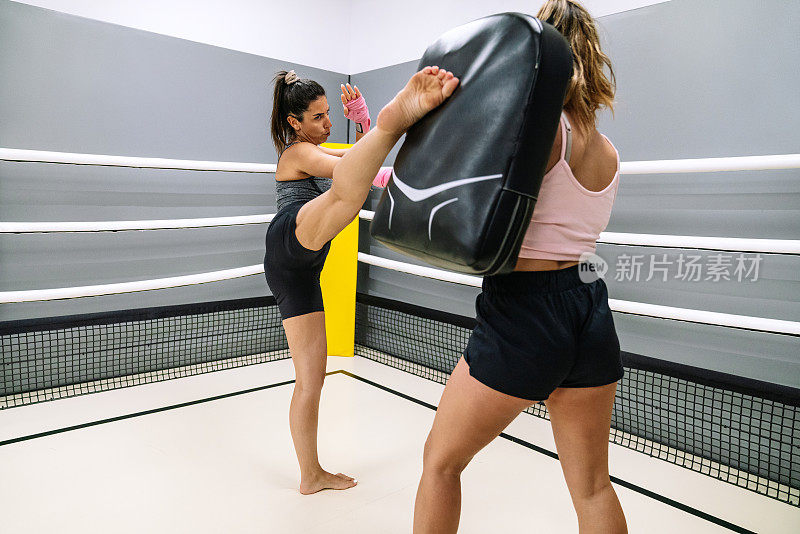 女自由搏击运动员练习高踢与她的教练在环