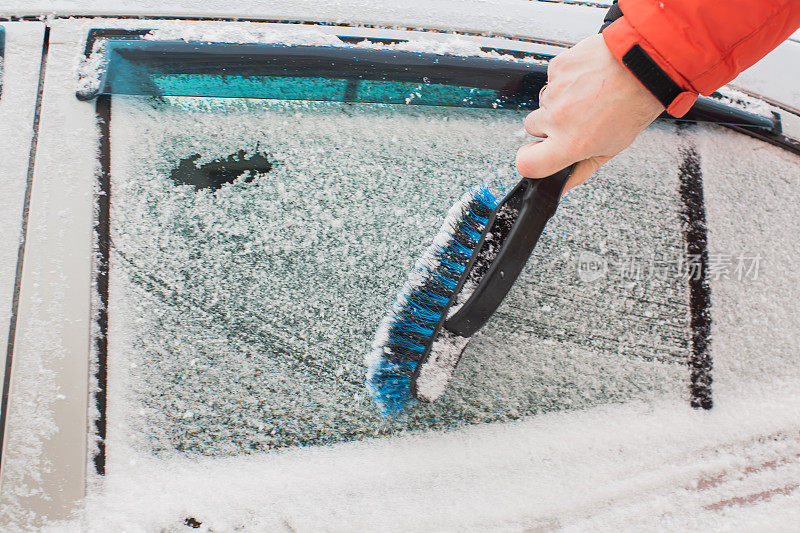 用刷子清理汽车上的积雪。雪下的汽车。冬天的天气。气候。风暴。运输
