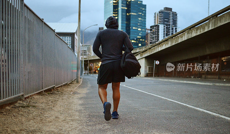 健身，黑人在跑步后走在城市街道上，晚上穿着卫衣锻炼和健身房锻炼。一名男子运动员背着行李袋在迈阿密市区散步和有氧训练