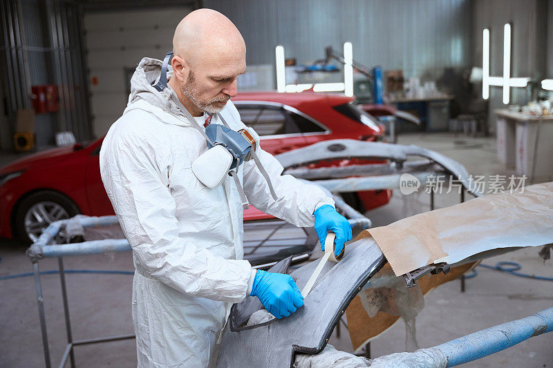 汽车修理厂工人准备汽车保险杠进行喷漆