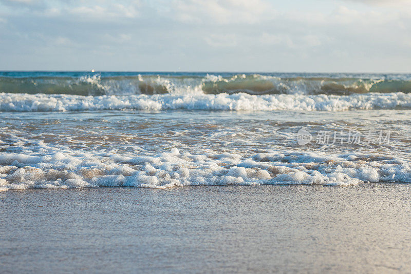 海浪涌向海滩，小浪拍打着沙滩。