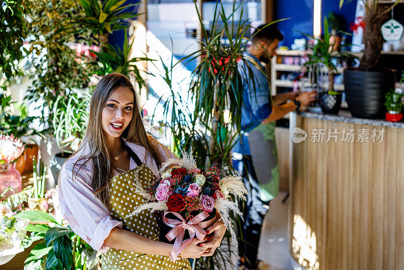 在一家现代花店里，一位美丽的女子手持鲜花。