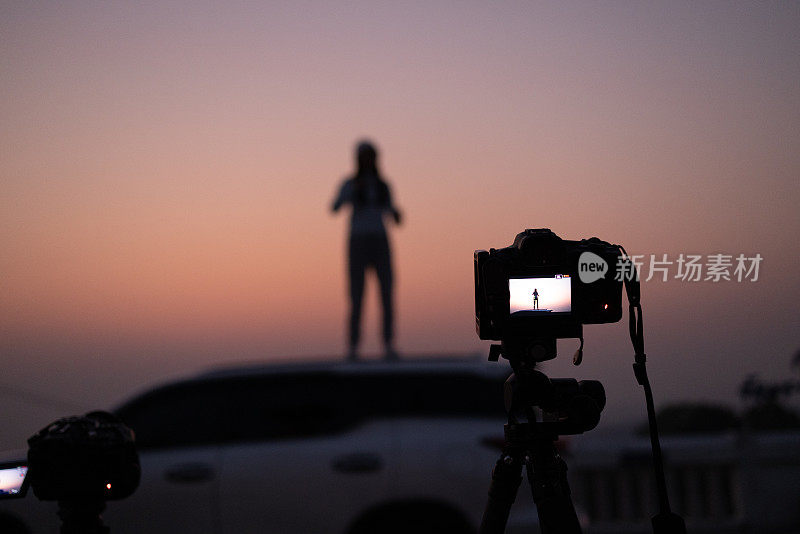 剪影运动女孩在SUV车顶晨练，女性旅游运动在车顶日出，旅行的生活方式概念