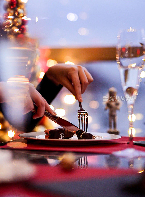 豪华餐厅餐桌上的香槟和圣诞糖果，特写镜头优雅的夫妇举杯庆祝香槟杯，夫妇在装饰着圣诞装饰的餐桌上庆祝圣诞节
