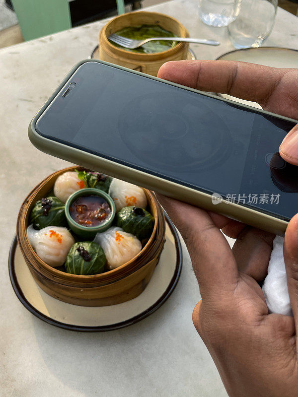 智能手机拍摄的混合美食momos在竹笼中，中间是一锅酱，壳形和卷心菜叶饺子，一种受欢迎的印度街头食品，社交媒体摄影，高架视图