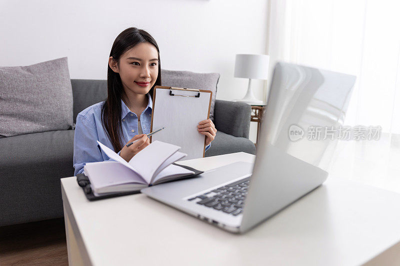 商业和教育概念。微笑的年轻黑人妇女坐在办公桌前，用笔记本电脑在纸质笔记本上写信，腾出了复印空间。快乐的千禧一代女性用电脑学习