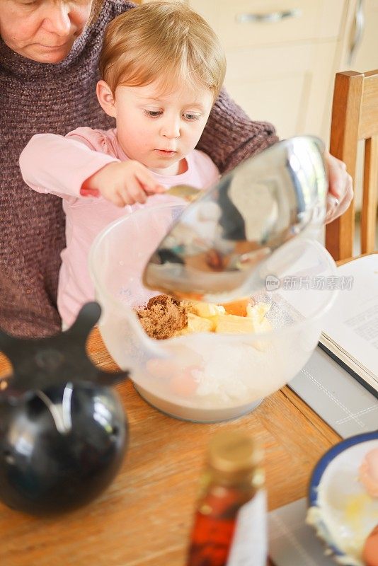祖母教她的孙子如何准备蛋糕混合物