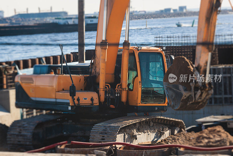 挖掘机在施工现场将沙子卸入自卸车，在道路施工期间进行挖掘和工作，反铲和自卸车卸载道路金属和砾石，施工新路
